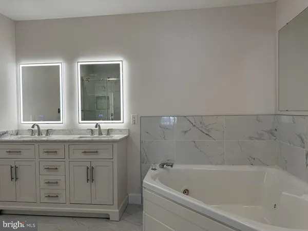 a bathroom with a granite countertop sink a large mirror a bathtub and next to a window