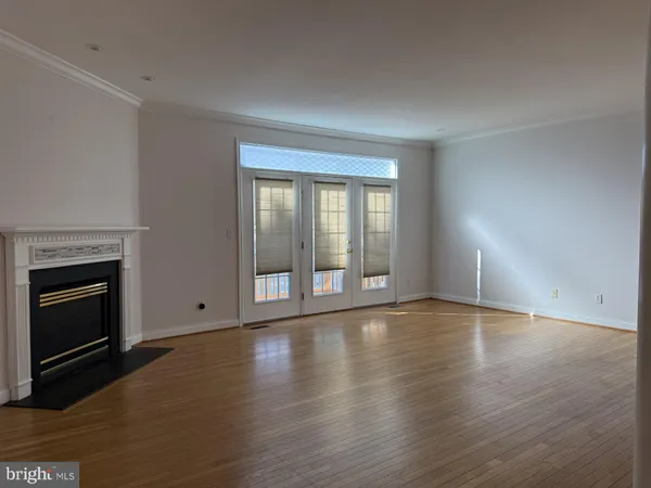 a view of an empty room with glass door and wooden floor