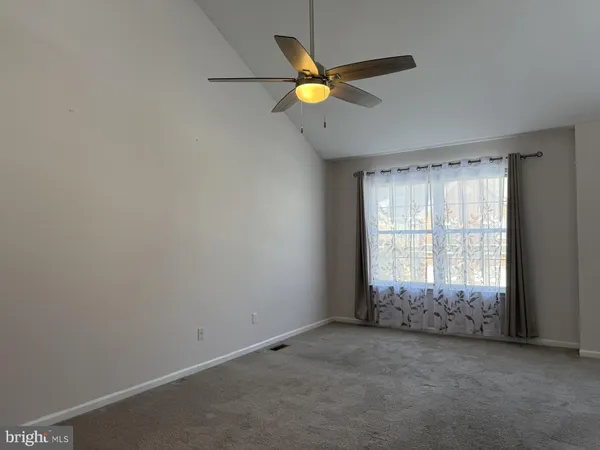 an empty room with ceiling fan and windows