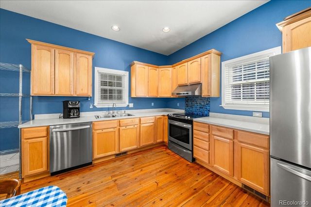 a kitchen with stainless steel appliances granite countertop wooden cabinets a stove a sink a window and island