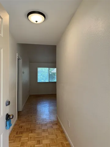 a view of an empty room with wooden floor and a window