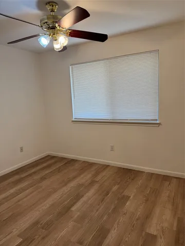 a view of an empty room with chandelier fan and a window