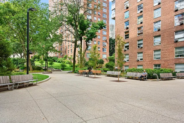 front view of a building with a bench and trees