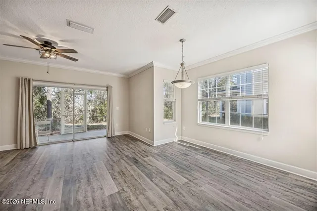 a view of an empty room with a window and wooden floor