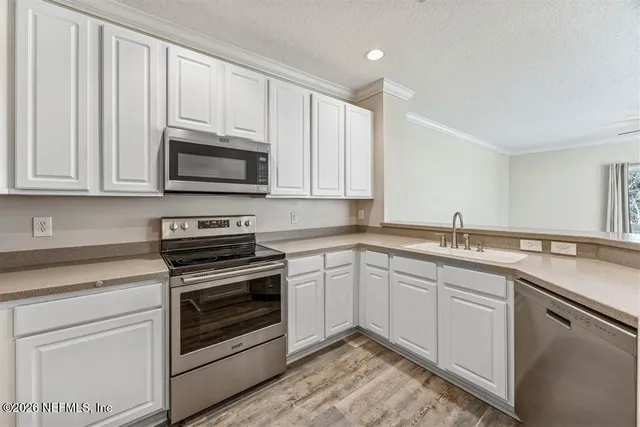 a kitchen with granite countertop white cabinets and stainless steel appliances