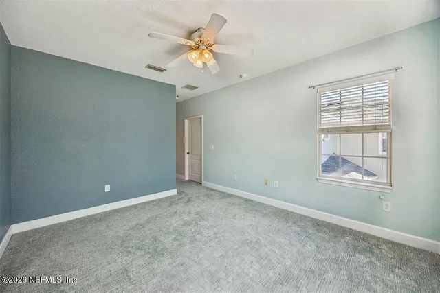an empty room with windows and chandelier fan