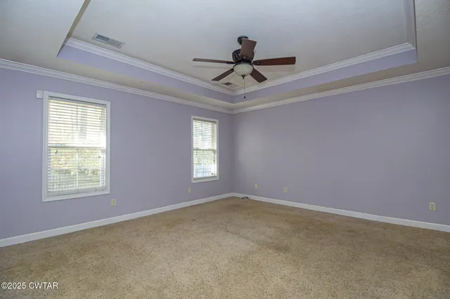 an empty room with windows and fan