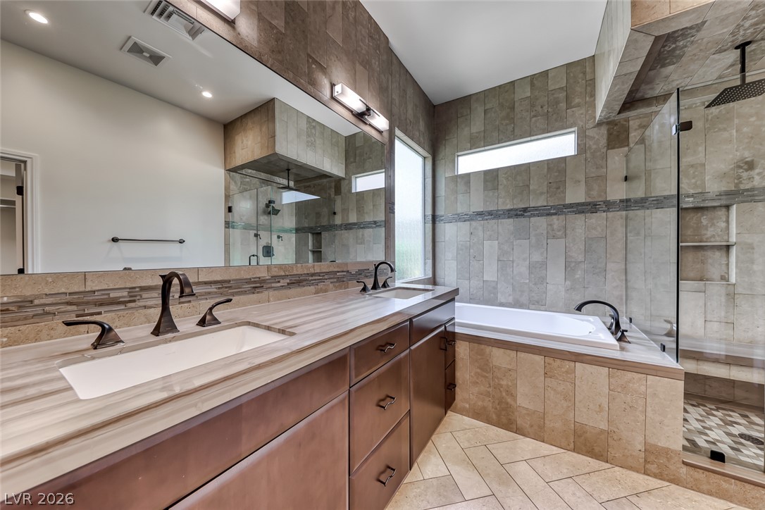 2122 Mooreview Street Henderson, NV 89012 - Photo 20 of 44 A refined bathroom featuring dual vanities, a deep soaking tub, and a spacious glass-enclosed shower.