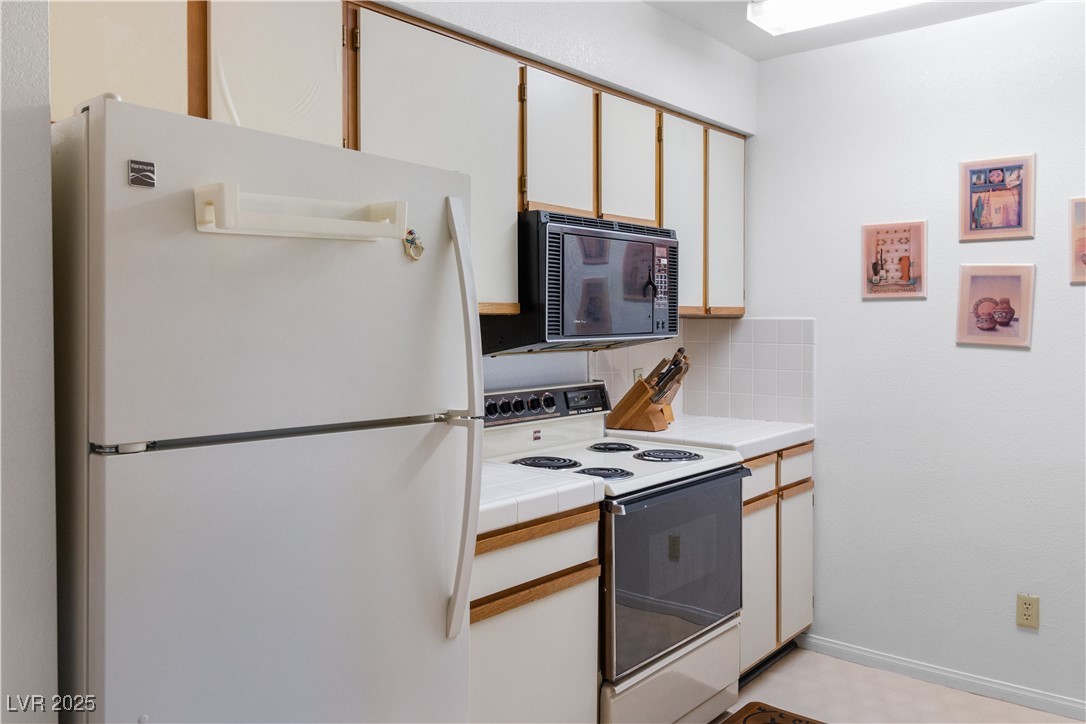 1928 Las Palmas Lane, Unit 228 Laughlin, NV 89029 - Photo 14 of 77 Kitchen featuring white appliances, backsplash, and tile counters