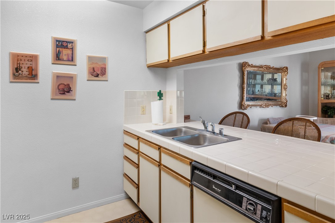 1928 Las Palmas Lane, Unit 228 Laughlin, NV 89029 - Photo 16 of 77 Kitchen featuring white dishwasher, a sink, tasteful backsplash, a peninsula, and baseboards