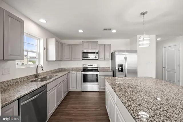 a large kitchen with granite countertop a sink and stainless steel appliances