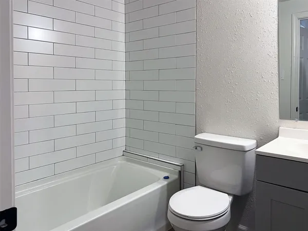 a white toilet and tub sitting next to a bathroom sink