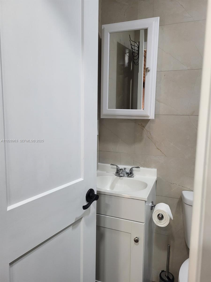 2137 Northwest 97th Street, Unit 2137 Miami, FL 33147 - Photo 17 of 19 a bathroom with a sink toilet and mirror
