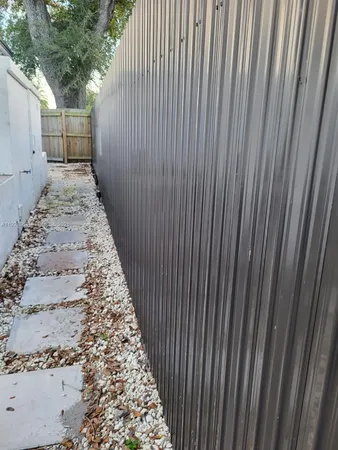a view of a backyard with large trees and wooden fence