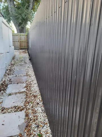 a view of a backyard with large trees and wooden fence
