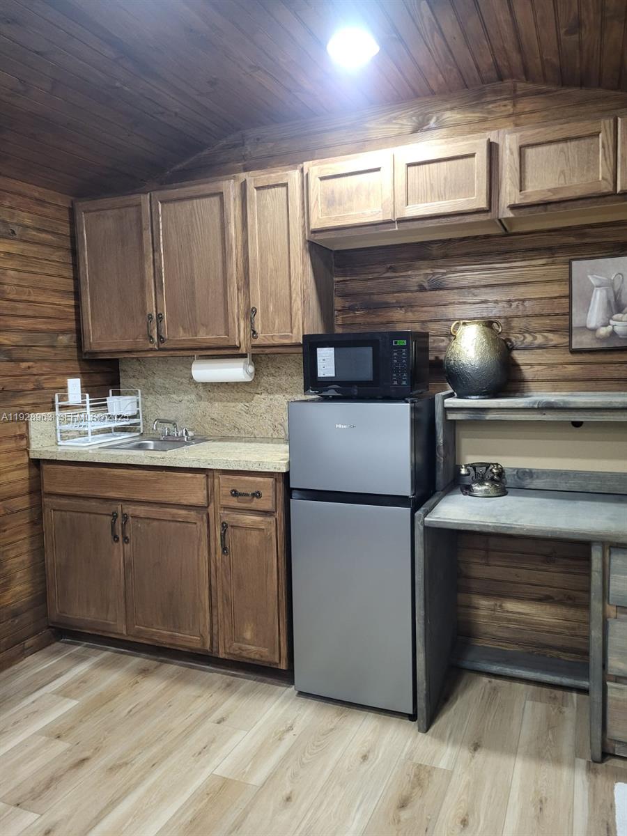 2137 Northwest 97th Street, Unit 2137 Miami, FL 33147 - Photo 8 of 19 a kitchen with kitchen island granite countertop wooden cabinets and white appliances