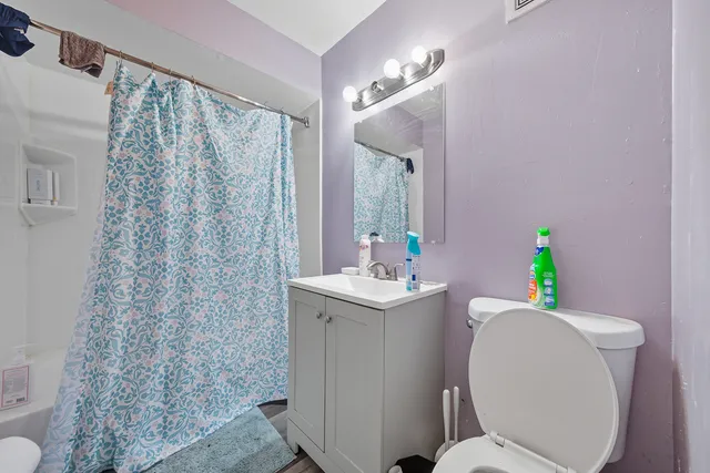 a bathroom with a sink a toilet a mirror and shower curtain