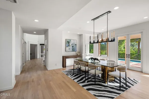 a view of a dining room and livingroom with furniture wooden floor a chandelier