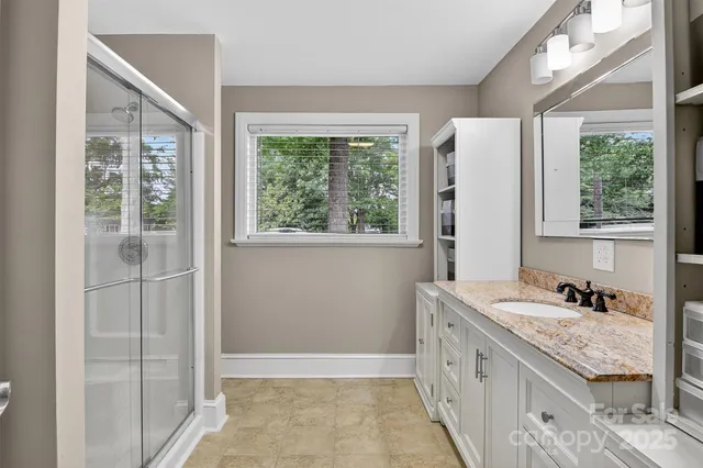a bathroom with a granite countertop sink and a window