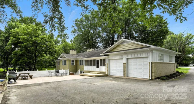 a view of a house with a yard and large tree