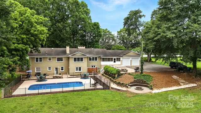a view of a house with a big yard potted plants and large tree