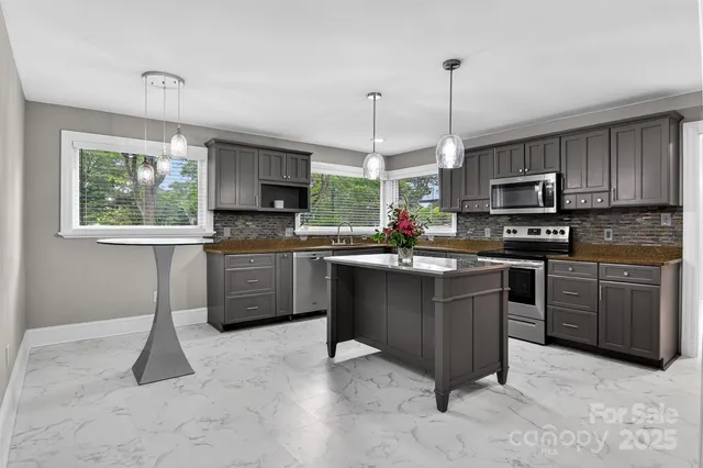 a kitchen with stainless steel appliances granite countertop a stove top oven a sink dishwasher a dining table and chairs