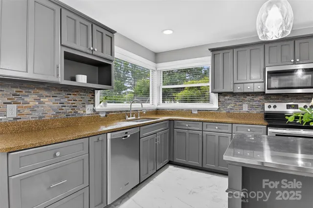 a kitchen with stainless steel appliances granite countertop a sink a stove and cabinets