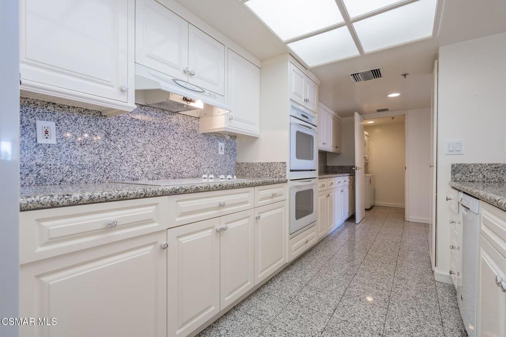 10660 Wilshire Boulevard, Unit 410 Los Angeles, CA 90024 - Photo 31 of 85 a kitchen with granite countertop white cabinets and white appliances