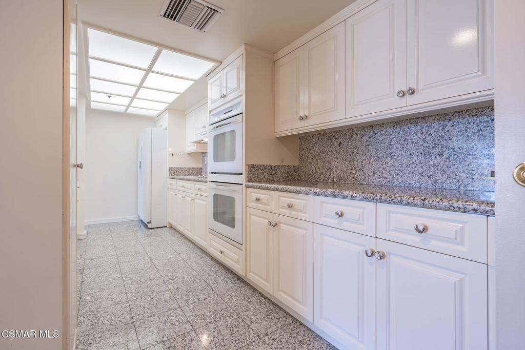 10660 Wilshire Boulevard, Unit 410 Los Angeles, CA 90024 - Photo 34 of 85 a kitchen with granite countertop white cabinets and white appliances