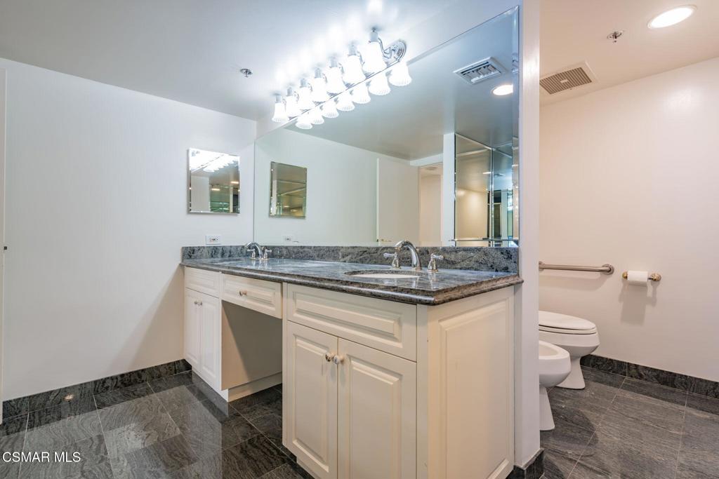 10660 Wilshire Boulevard, Unit 410 Los Angeles, CA 90024 - Photo 51 of 85 a bathroom with a granite countertop sink a toilet and a mirror