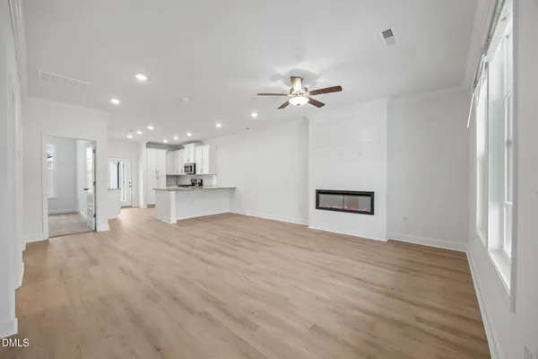 a view of an empty room with wooden floor and a ceiling fan