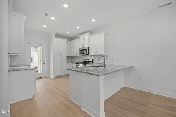 a kitchen with granite countertop cabinets stainless steel appliances and wooden floor