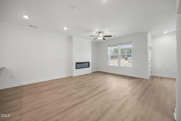 an empty room with wooden floor chandelier fan and windows