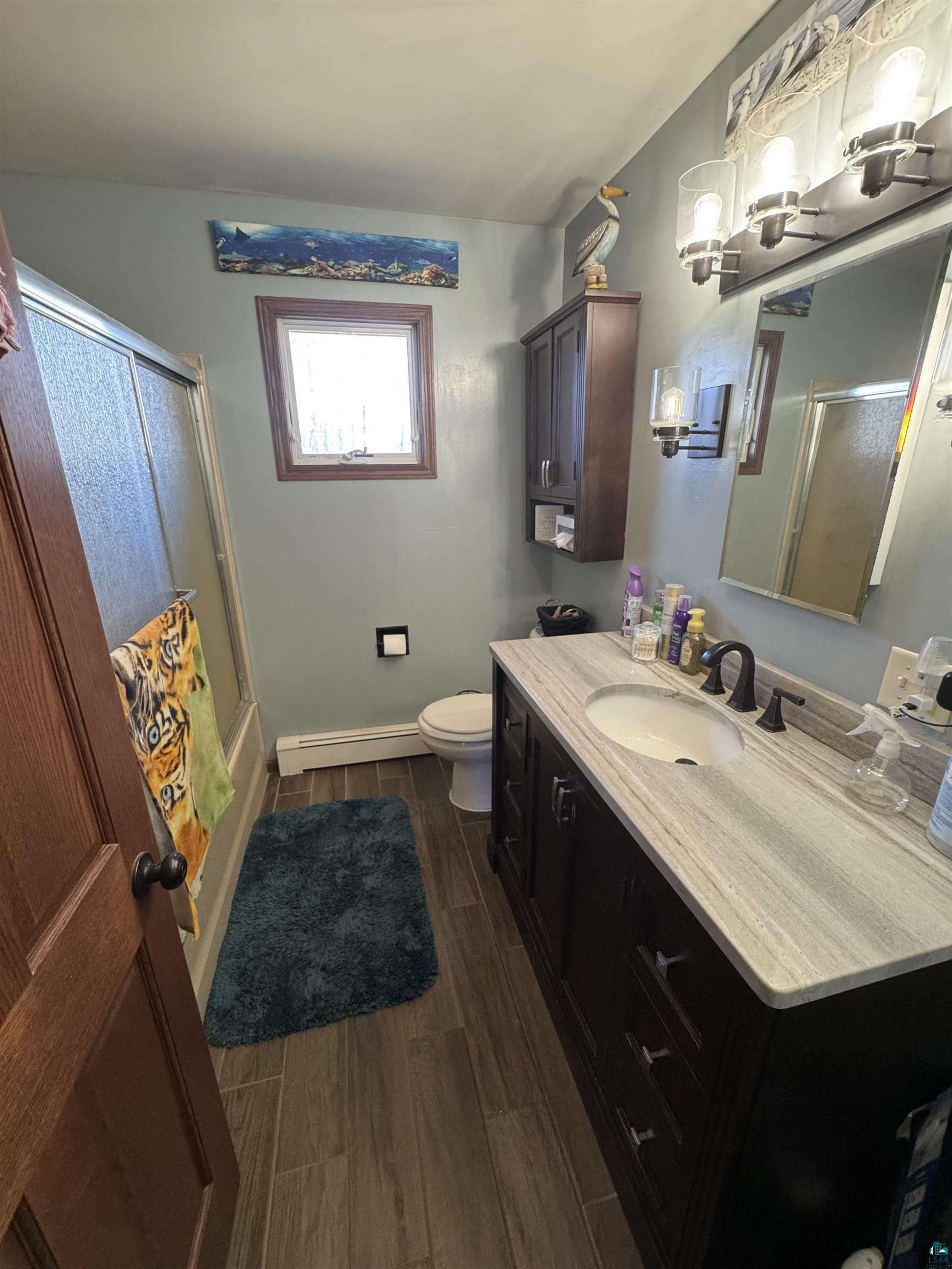 5133 East County Rd C Superior, WI 54880 - Photo 8 of 16 Bathroom featuring baseboards, baseboard heating, wood tiled floor, a tub/shower, and vanity