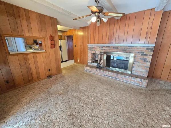 a view of a livingroom with a fireplace a ceiling fan and staircase