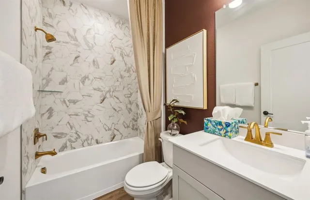 a bathroom with a bathtub sink mirror vanity and toilet
