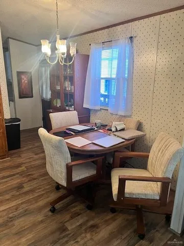 a dining room with wooden floor a chandelier a wooden table and chairs