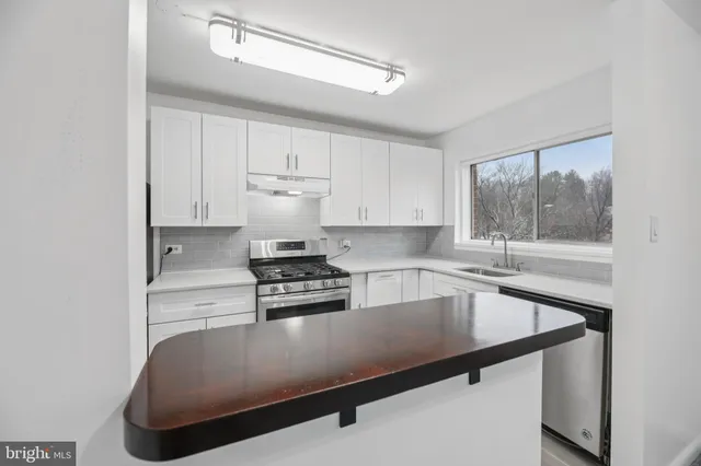 a kitchen with stainless steel appliances granite countertop a sink a stove and white cabinets