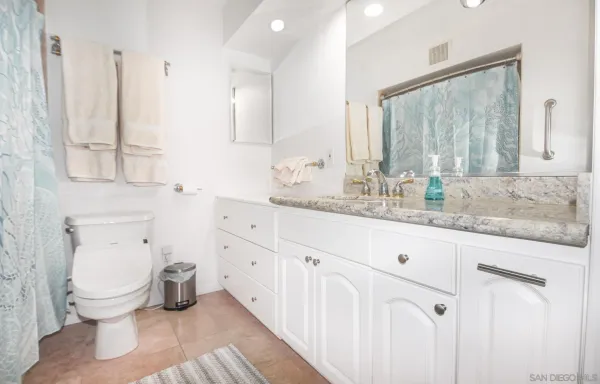 a bathroom with a granite countertop toilet sink and mirror