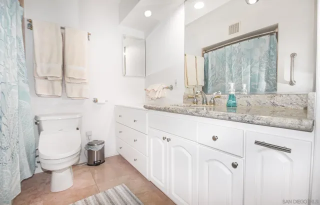a bathroom with a granite countertop toilet sink and mirror