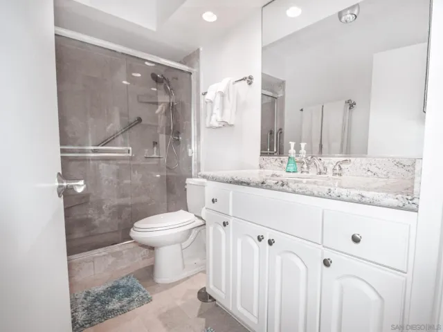 a bathroom with a granite countertop sink toilet and shower