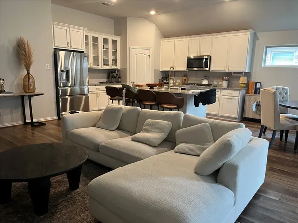 a living room with furniture a kitchen view and a refrigerator