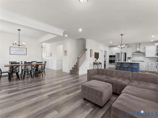 a large kitchen with kitchen island a sink a stove a refrigerator and white cabinets with wooden floor