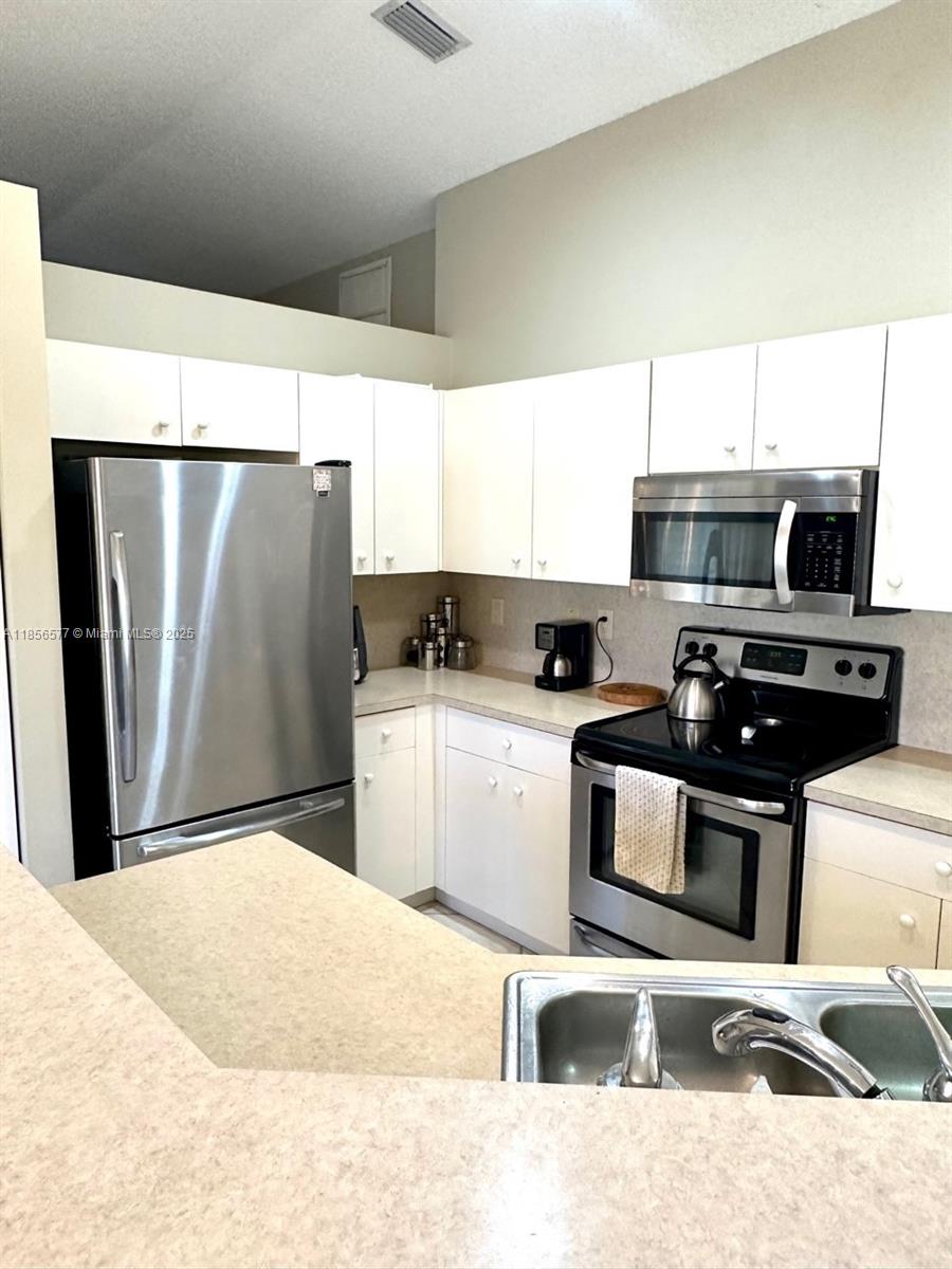 4370 Pine Ridge Court Weston, FL 33331 - Photo 12 of 39 a kitchen with stainless steel appliances kitchen island sink refrigerator and stove