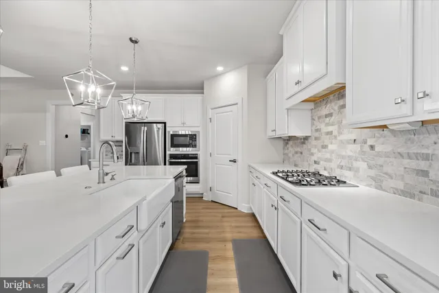 a kitchen with stainless steel appliances granite countertop a stove a kitchen island white cabinets and chairs