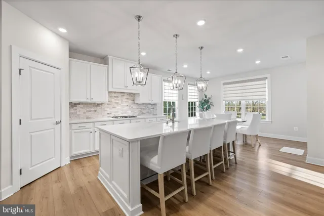 a large white kitchen with kitchen island white cabinets and stainless steel appliances
