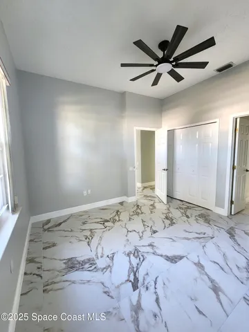 a view of a big room with windows and chandelier fan