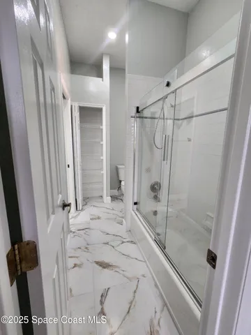 a view of a big room with wooden floor and windows