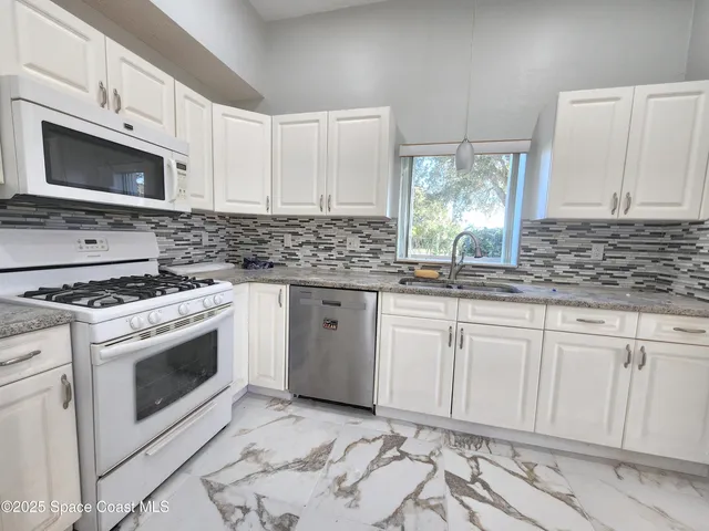 a kitchen with granite countertop a stove sink and cabinets