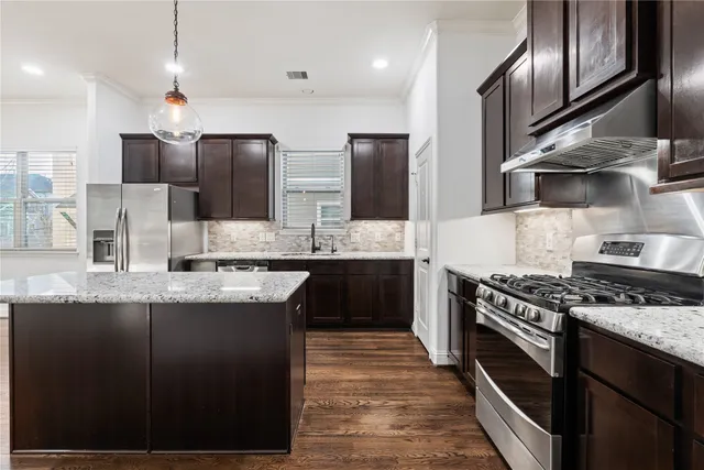 a kitchen with kitchen island granite countertop a sink stove and refrigerator